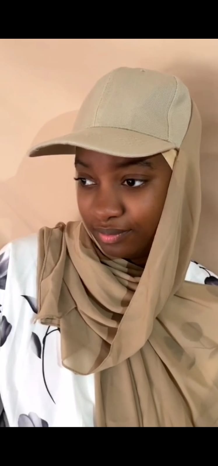 Casquette voilée beige portée, vue de trois quarts avec le voile drapé autour du cou et sur les épaules.